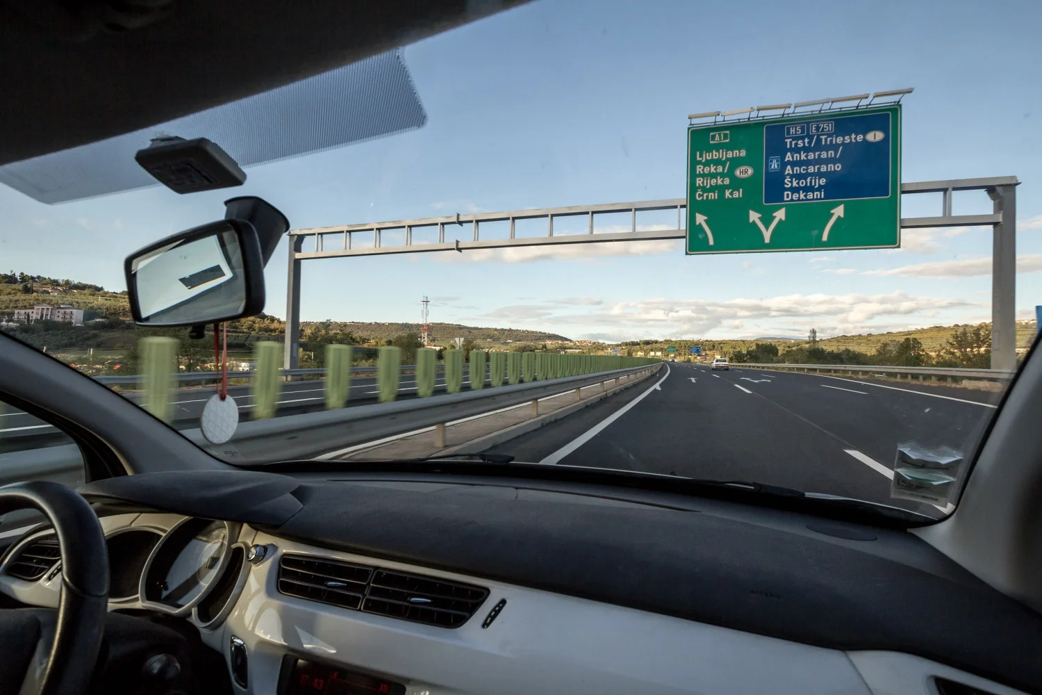 Zicht vanuit de binnenkant van een voertuig op een snelweg met bewegwijzering in Slovenië.